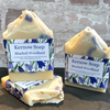 Three bars of Kernow Soap with Bluebell Woodland scent on a stone surface against a brick wall background.