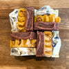 Assorted bars of soap in various colors and textures on a wooden surface