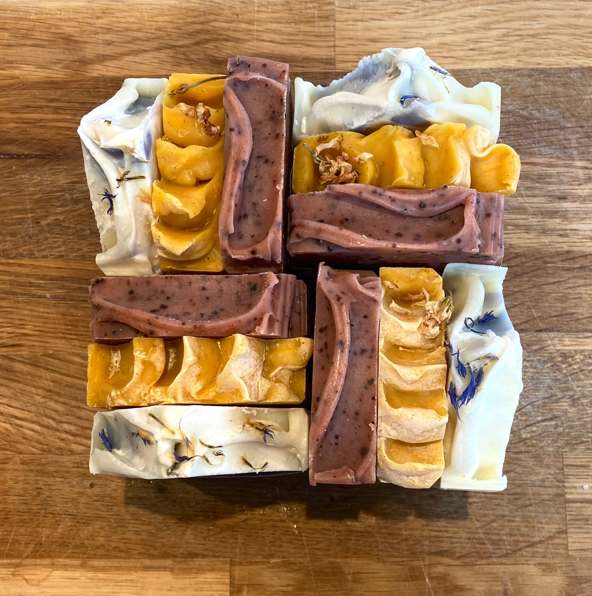 Assorted bars of soap in various colors and textures on a wooden surface