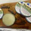 Bug Off Balm containers on a wooden board with lavender on a marble background