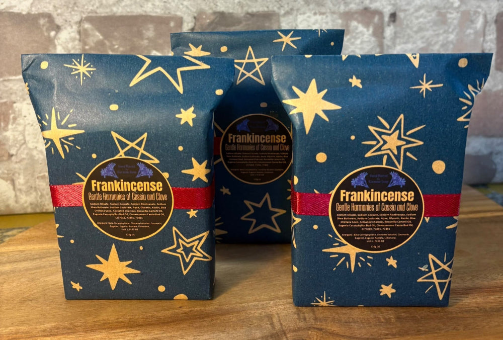 Three bars of wrapped Kernow Soap - Frankincense with a brick background on a wooden surface