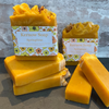 Yellow soap bars with 'Kernow Soap' packaging on a gray surface and brick wall background.
