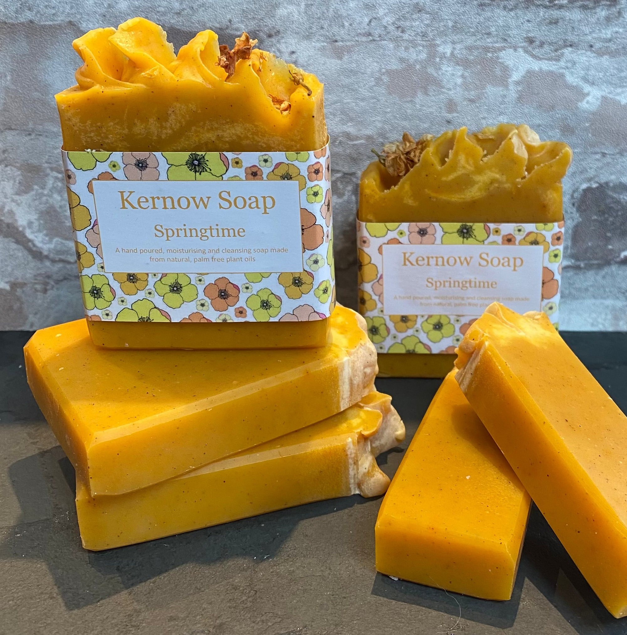 Yellow soap bars with 'Kernow Soap' packaging on a gray surface and brick wall background.