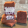 Stack of Kernow Soap Rosehip soap bars with a decorative label against a stone wall background.