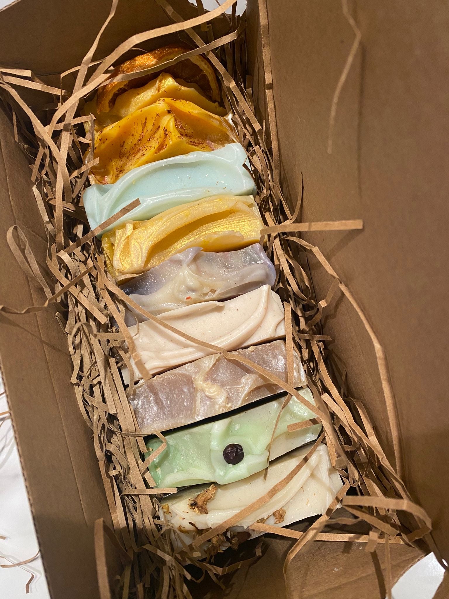 Assorted colorful soap bars in a box with straw padding