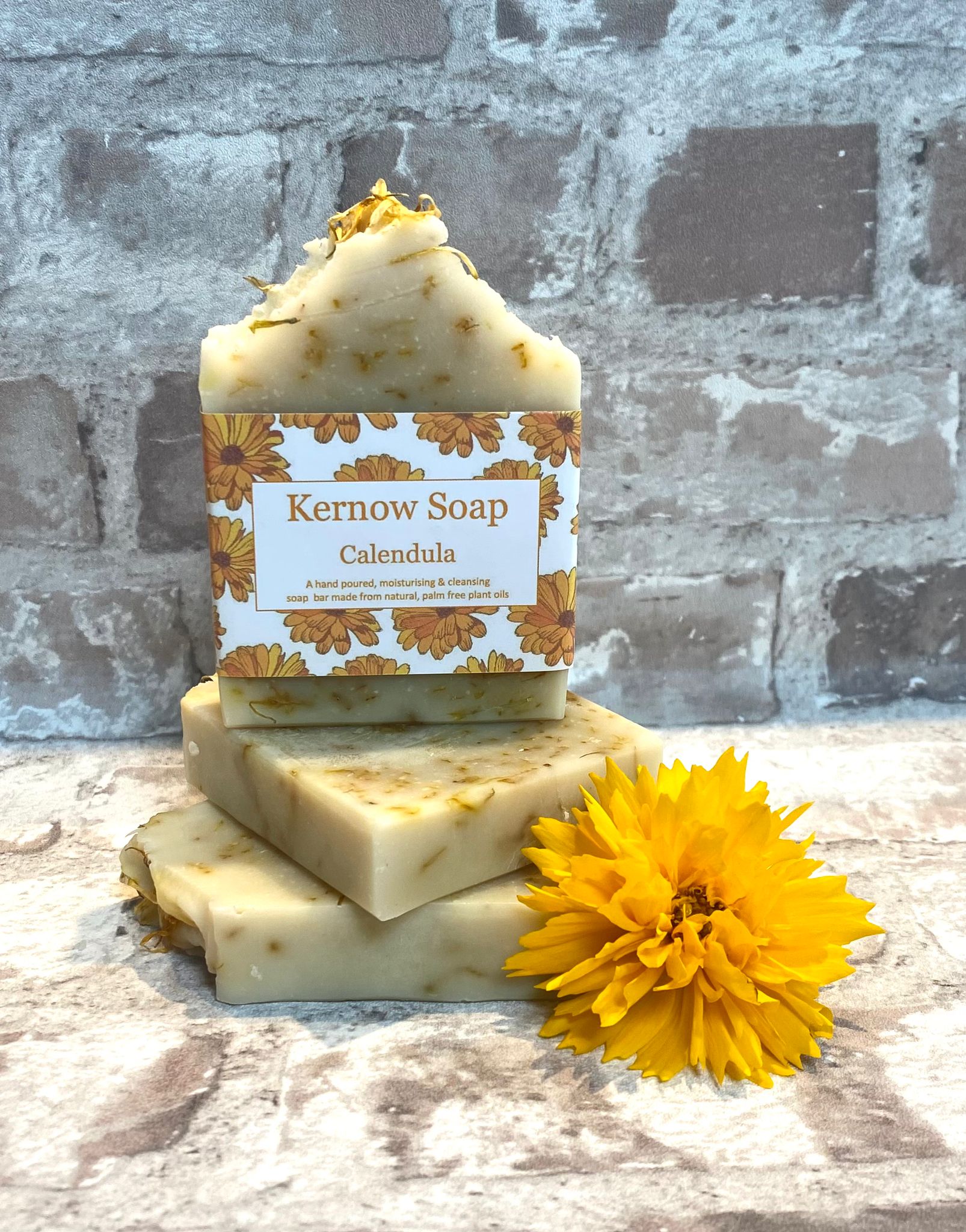 A stack of three bars of calendula soap one labelled, two unlabelled.
