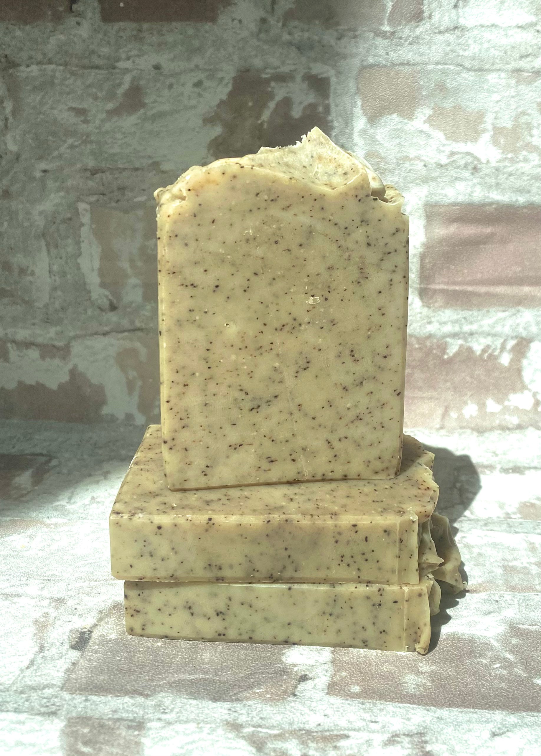 A large bars of gardeners hand soap with a rough, textured surface, sitting on a textured brick wall. 