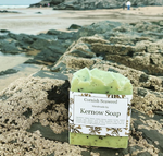 A bar of seaweed soap with a beach and sea in the background.