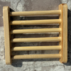 A small rectangular wooden slat rack or shelf with six vertical wooden bars, mounted against a textured gray concrete wall.