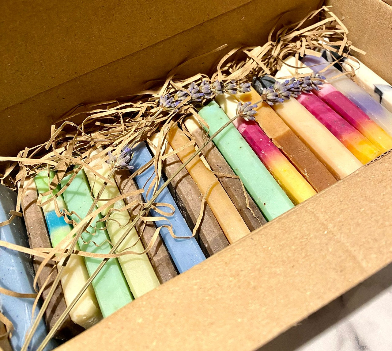 Set of colourful soap ends in a cardboard box with dried herbs and lavender
