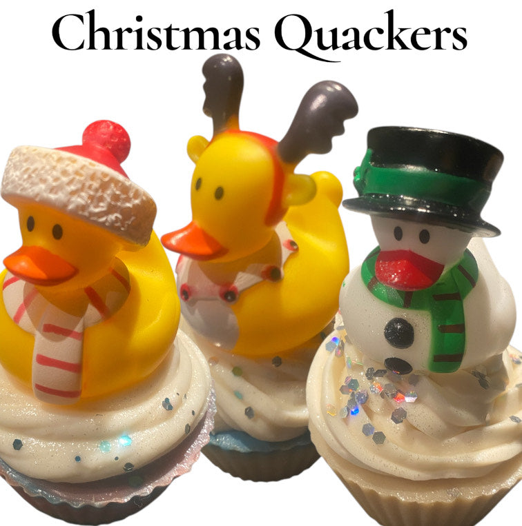 Three cupcakes with Christmas-themed decorations including rubber ducks and a snowman.